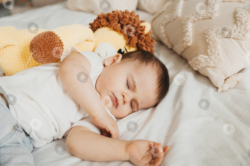 Скачать Спящий ребенок в кроватке, держащий на руках плюшевого львенка. фотосток Ozero