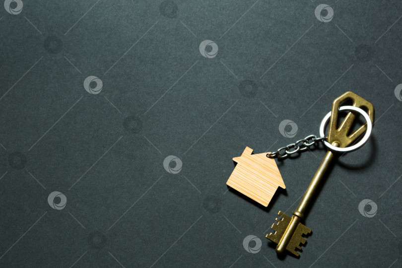 Скачать Брелок для ключей в форме дома с ключом на черном фоне. Строительство, дизайн, проект, переезд в новый дом, ипотека, депозит, аренда и покупка недвижимости. Пространство для копирования фотосток Ozero