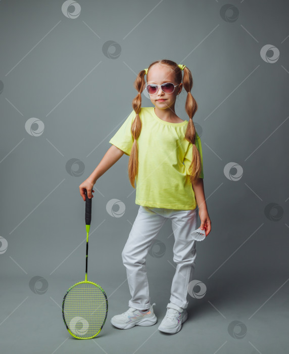 Скачать маленькая девочка держит ракетку на сером фоне. маленький игрок в теннис. Маленький ребенок играет в теннис. детский спорт. фотосток Ozero