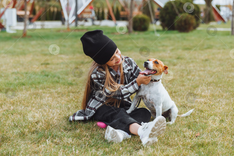 Скачать маленькая девочка играет со своей собакой на траве в парке. джек Рассел терьер. ребенок дарит игрушку своей собаке. фотосток Ozero