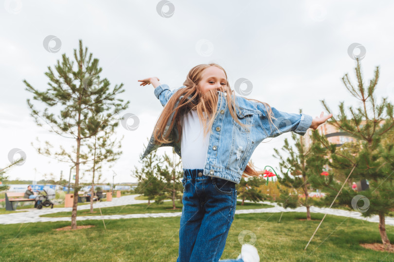 Скачать Маленькая девочка с длинными волосами весело прыгает по улице. Концепция счастливого детства. фотосток Ozero