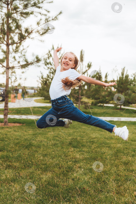 Скачать Маленькая девочка с длинными волосами весело прыгает по улице. Концепция счастливого детства. фотосток Ozero