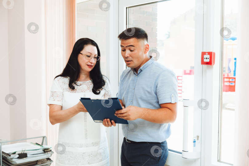 Скачать Два деловых человека, мужчина и женщина, обсуждают работу в офисе. фотосток Ozero