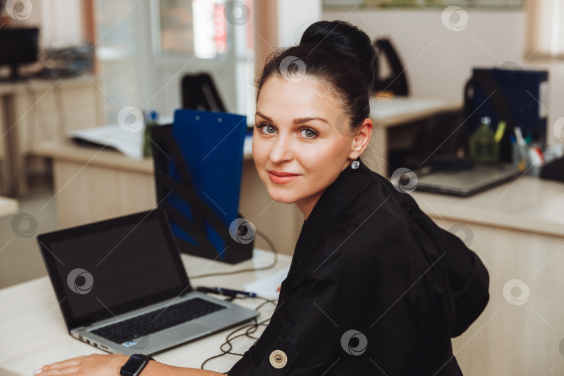 Скачать Портрет улыбающейся симпатичной деловой женщины, сидящей на своем рабочем месте. деловая брюнетка в офисе фотосток Ozero