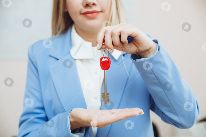 Скачать деловая женщина сидит в офисе и держит в руке ключи. фотосток Ozero