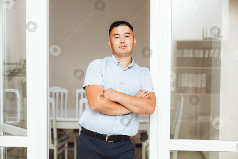 Скачать Молодой азиатский бизнесмен, скрестивший руки на груди в офисе. портрет делового человека фотосток Ozero