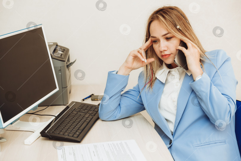 Скачать Молодая женщина разговаривает с клиентом по телефону в офисе. женщина в деловом костюме работает в офисе фотосток Ozero