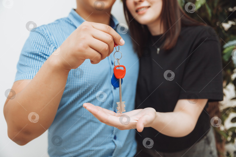 Скачать Счастливая супружеская пара празднует переезд в новый дом, показывает ключи, стоит в квартире, концепция ипотеки на недвижимость.ключи крупным планом фотосток Ozero