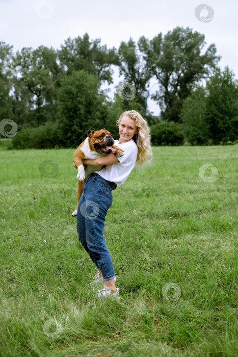 Скачать young woman playing with English Bulldog at park фотосток Ozero