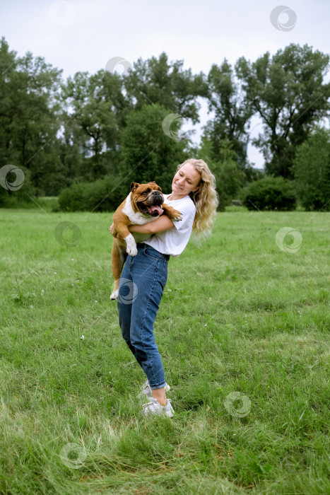 Скачать молодая женщина играет с английским бульдогом в парке фотосток Ozero