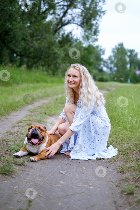 Скачать молодая женщина играет с английским бульдогом в парке фотосток Ozero