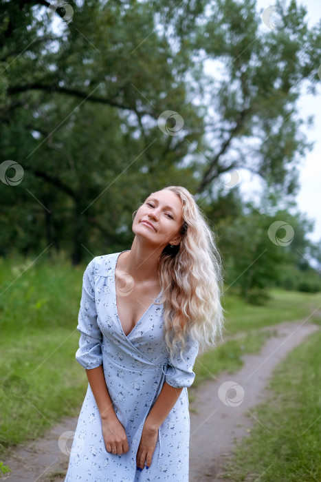 Скачать Портрет светловолосой женщины в парке. Молодая женщина в синем винтажном платье. Женщина прогуливается на летней природе. Длинные волосы. фотосток Ozero