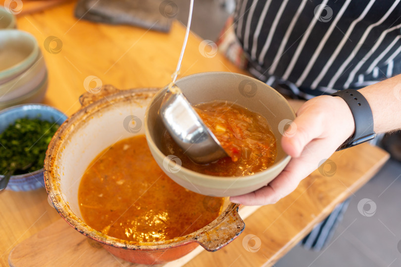 Скачать Повар наливает суп в тарелку фотосток Ozero