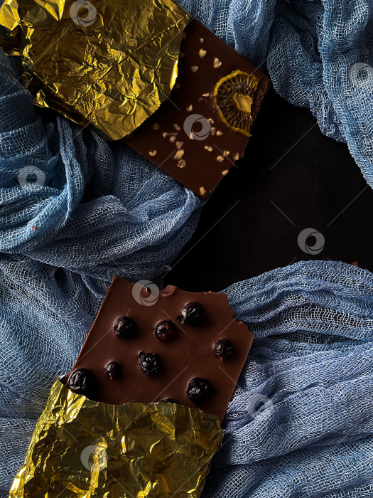 Скачать Шоколад с ягодами, киви, орехами в золотой фольге на голубом и черном фоне фотосток Ozero