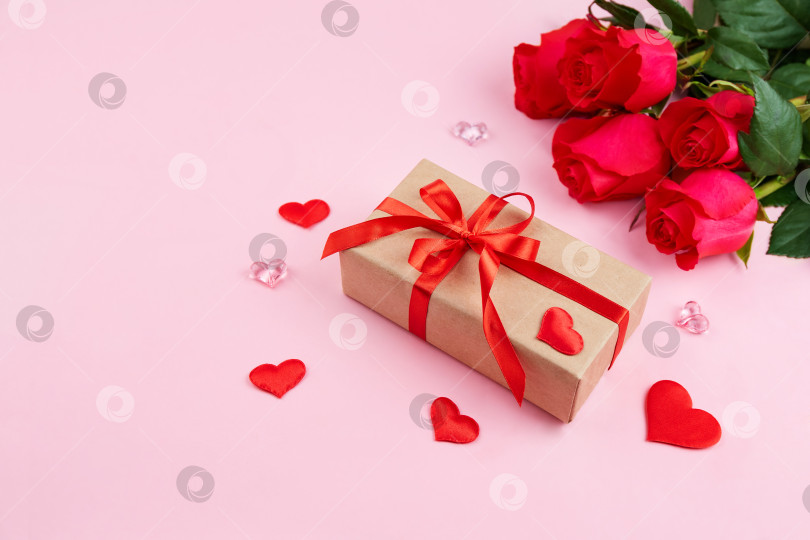 Скачать Букет красных роз, коробка в упаковке из крафт-бумаги с красной лентой и украшениями в форме сердечек фотосток Ozero