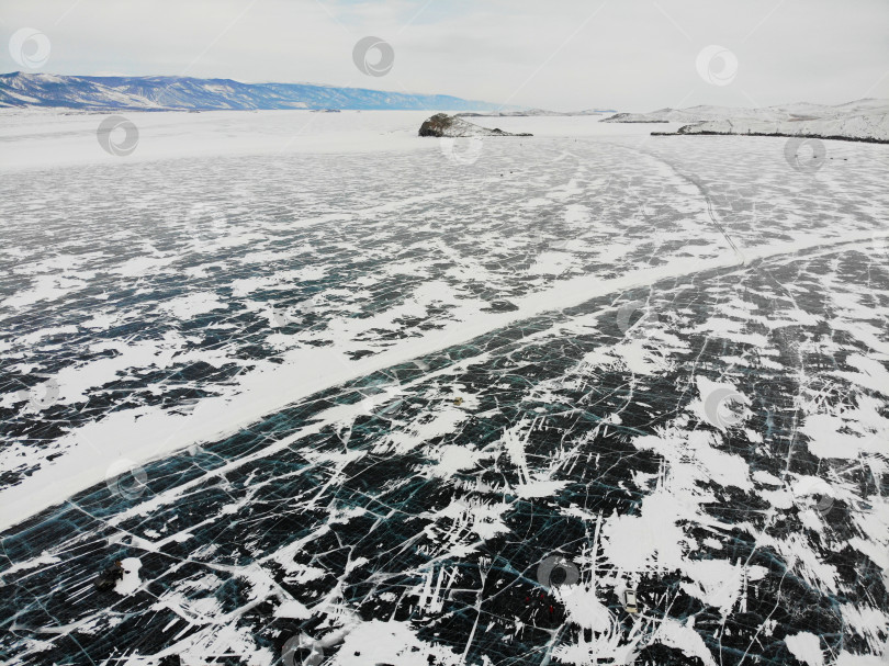 Скачать Вид на замерзшее зимой озеро Байкал с воздуха. Машины едут по ледяной дороге фотосток Ozero
