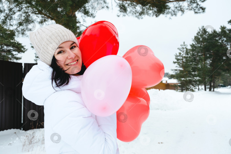 Скачать Счастливая женщина с воздушными шарами в форме сердца на открытом воздухе зимой со снегом. День святого Валентина, любовь и увлечение, подарок от парня, признание в любви, образ жизни фотосток Ozero