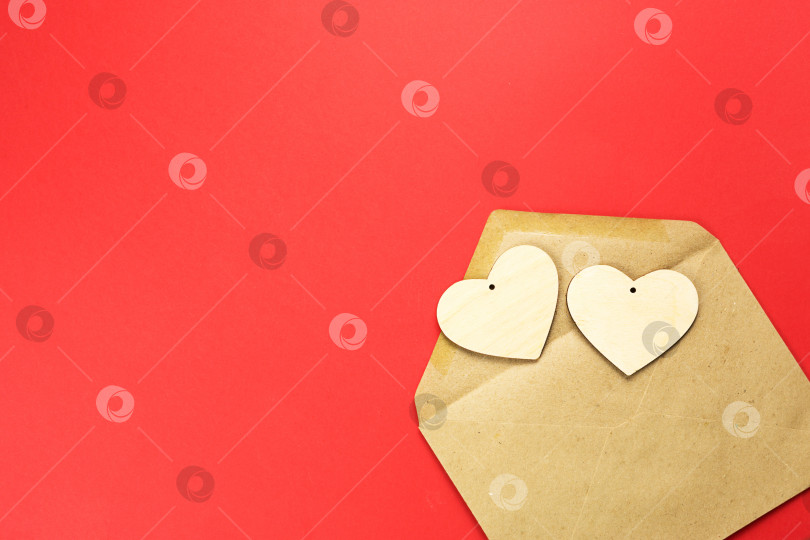 Скачать Деревянные сердечки высыпаются из открытого конверта на красном фоне. День святого Валентина, любовное письмо, признание в любви, знакомство. Пространство для копирования, макет фотосток Ozero