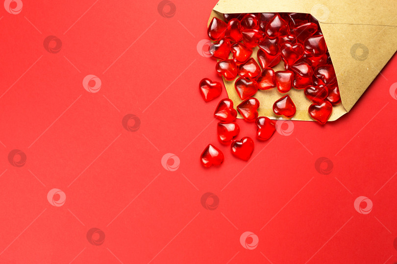 Скачать Стеклянные сердечки высыпаются из открытого конверта на красном фоне. День святого Валентина, любовное письмо, признание в любви, знакомство. Место для копирования, макет фотосток Ozero