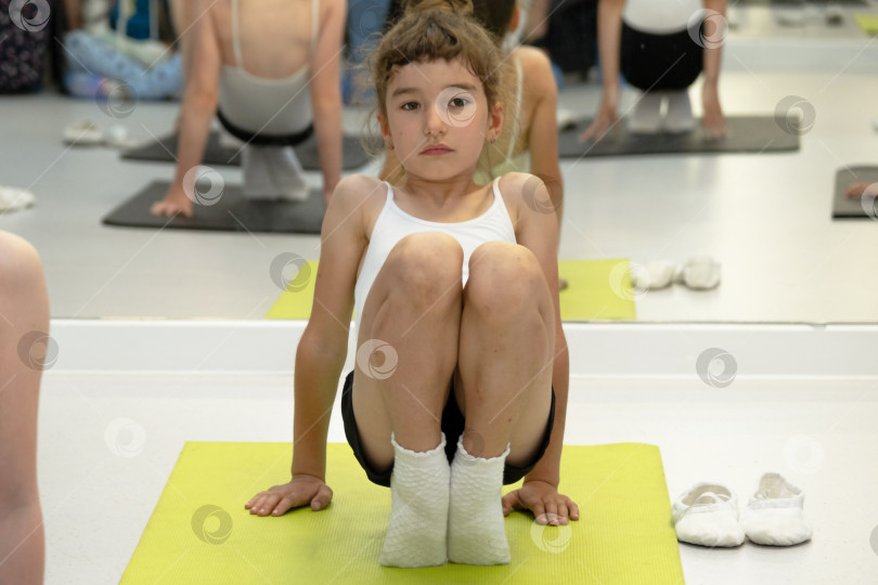 Скачать Ребенок тренируется в тренажерном зале на коврике, выполняет упражнения на растяжку и пресс, гимнастику и общефизическую спортивную подготовку. Работа над собой и своим телом с детства, преодоление себя фотосток Ozero