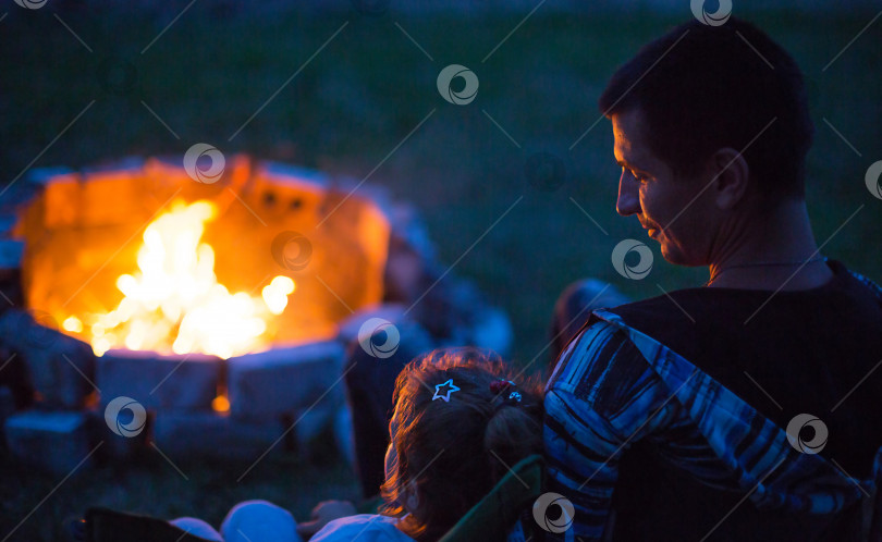 Скачать Папа и дочь сидят ночью у костра на открытом воздухе летом на природе. Семейный поход фотосток Ozero