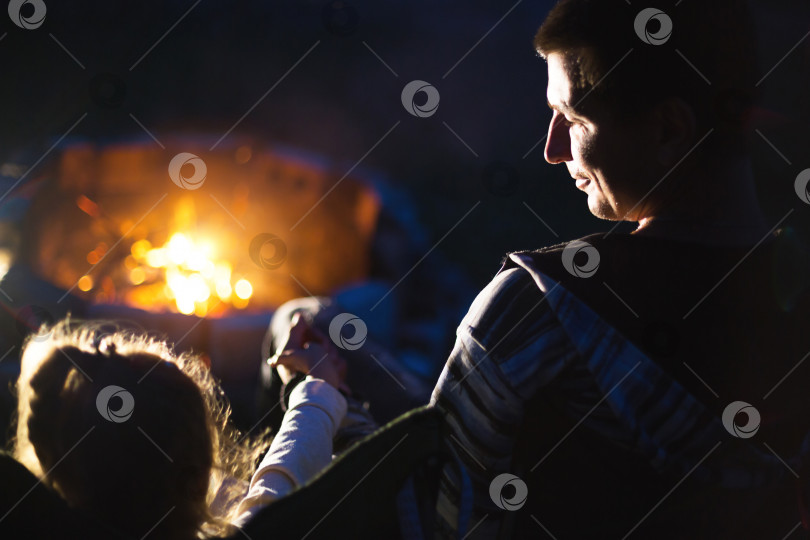 Скачать Папа и дочь сидят ночью у костра на открытом воздухе летом на природе. Семейный поход фотосток Ozero