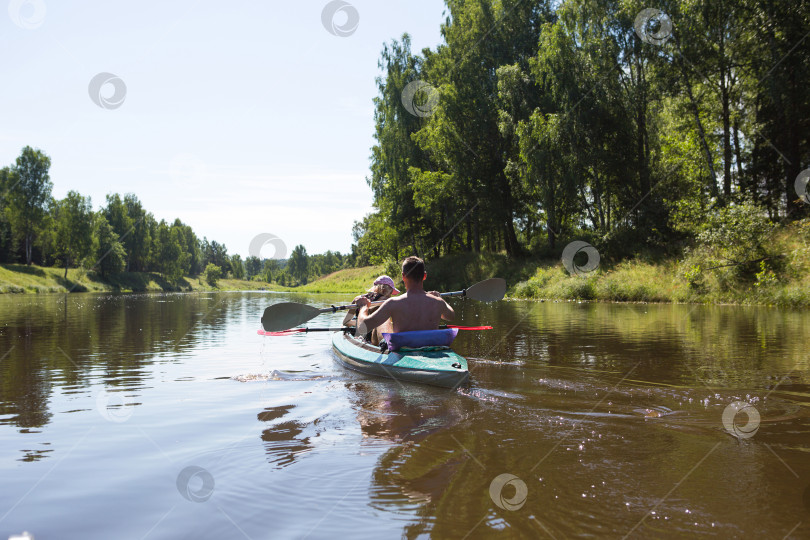Скачать Летом пара мужчин и женщин катаются на байдарках по реке. Активный отдых, семейные путешествия, экстремальные приключения, спортивный и экологический внутренний туризм. Снаряжение для рафтинга, лодка, весла. фотосток Ozero