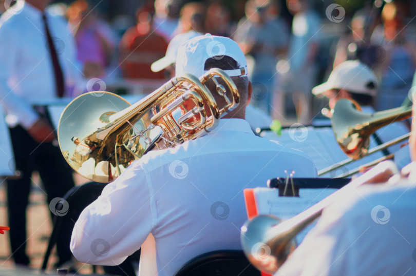 Скачать Выступление джаз-бэнда на открытой городской сцене летним вечером. Группа музыкантов, играющих на духовых инструментах, на солнце. Избирательный фокус фотосток Ozero