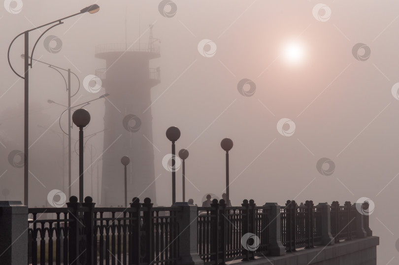 Скачать Старый маяк в тумане на отремонтированной набережной с фонарями. Солнечный диск с красным ореолом. Благовещенск, Дальний Восток, Россия фотосток Ozero