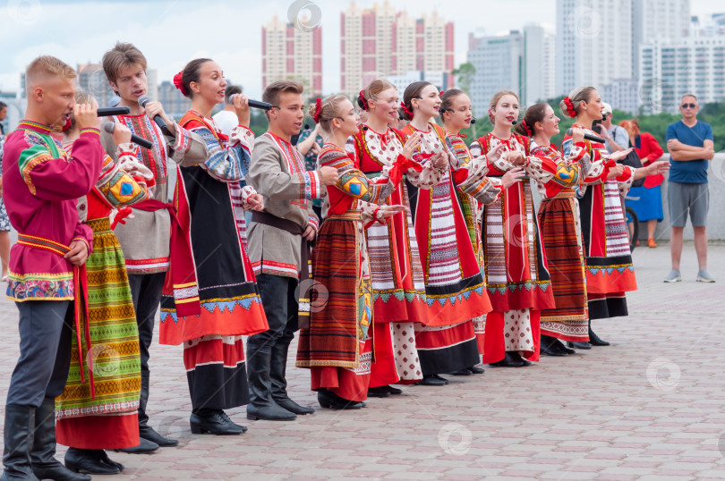 Скачать БЛАГОВЕЩЕНСК, РОССИЯ - 15 июля 2023 года: Выступление творческой группы в русских народных костюмах на набережной. Ансамбль песни и пляски выстраивается в шеренгу и хором исполняет русскую народную песню фотосток Ozero