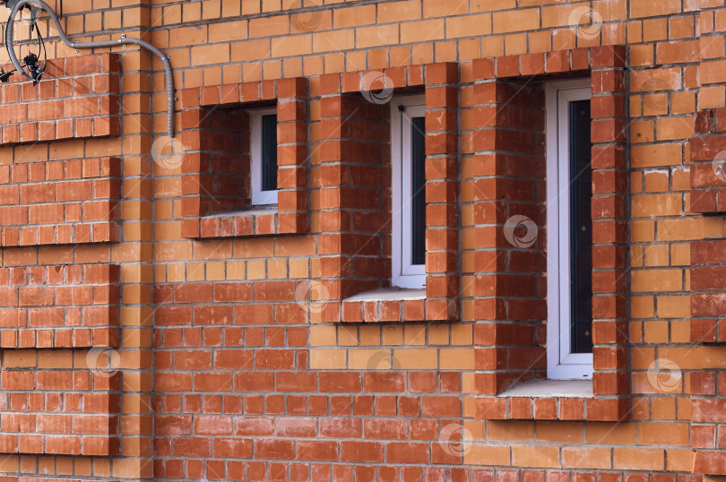 Скачать Минималистичный снимок кирпичной стены с окнами разного размера. Три окна с пластиковыми рамами. Кладка из красного кирпича. Фасад здания необычного дизайна фотосток Ozero