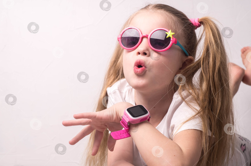 Скачать Технология для детей: девочка в розовых очках пользуется умными часами. фотосток Ozero