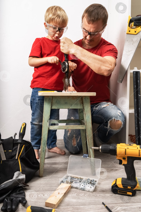 Скачать Отец учит сына работать с ручной дрелью. фотосток Ozero