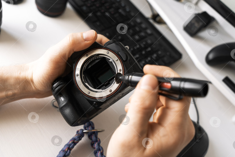 Скачать Мужчина очищает матрицу фотоаппарата от пыли специальным карандашом. фотосток Ozero