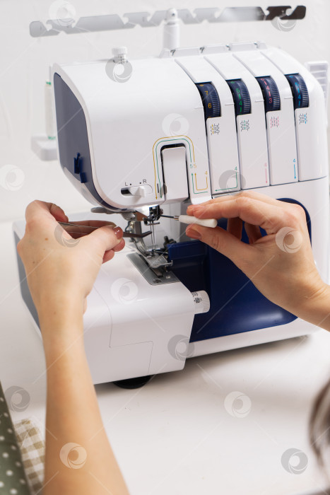 Скачать Женщины за работой: Девушка вдевает нитку в иглу швейной машинки. фотосток Ozero