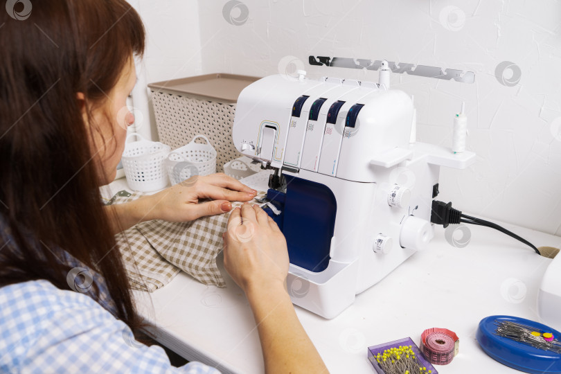 Скачать Женщины за работой: девушка-портниха делает шов на швейной машинке. фотосток Ozero