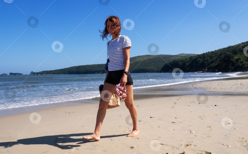 Скачать Счастливая загорелая молодая женщина прогуливается по песчаному пляжу, расслабляясь и наслаждаясь летними путешествиями фотосток Ozero