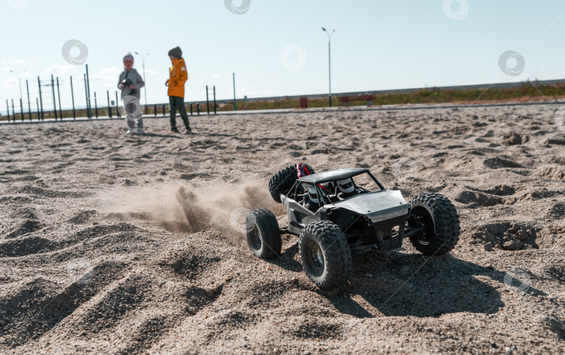 Скачать Игривые малыши управляют радиоуправляемым внедорожным высокоскоростным спортивным багги на песке черный внедорожник rc фотосток Ozero