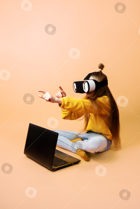 Скачать Девушка-школьница в очках виртуальной реальности с ноутбуком на коленях на розовом фоне. фотосток Ozero