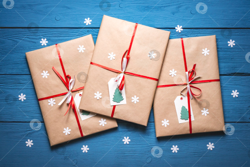 Скачать Подарочная бумажная упаковка с красной лентой на синих досках с белыми снежинками фотосток Ozero