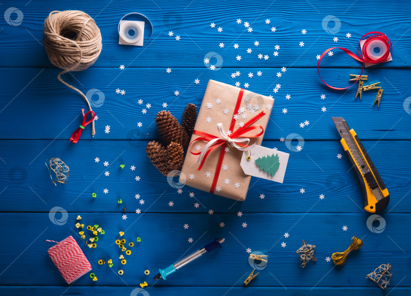 Скачать скрапбукинг. Упаковка рождественского подарка в крафт-бумагу на синем деревянном фоне фотосток Ozero