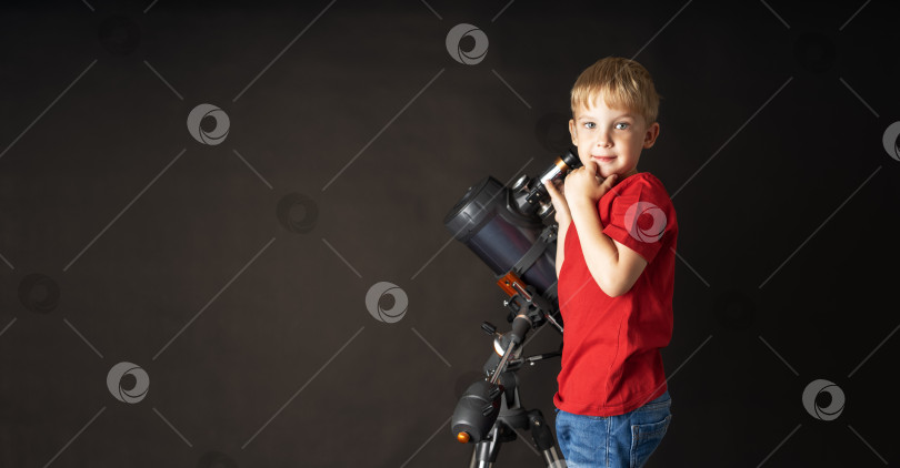 Скачать Маленький мальчик в красном футбольном мяче стоит рядом с большим телескопом. фотосток Ozero