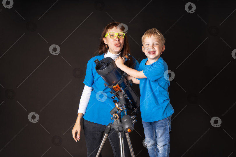 Скачать Мама и сын весело изучают большой огнеупорный телескоп и показывают язык. фотосток Ozero