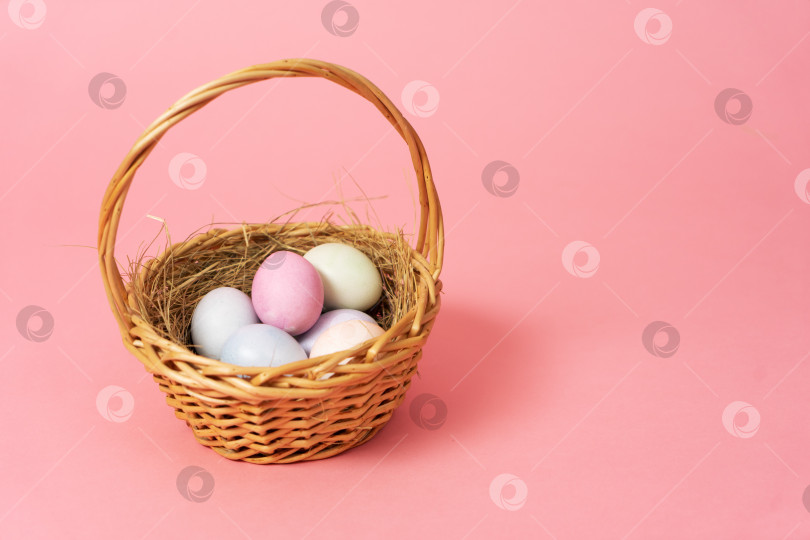 Скачать Счастливой Пасхи: корзина с разноцветными яйцами на розовом фоне. фотосток Ozero