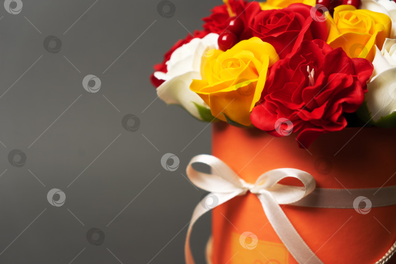 Скачать Цветы в цвету: Букет красных и желтых роз в круглой коробке на сером фоне. фотосток Ozero