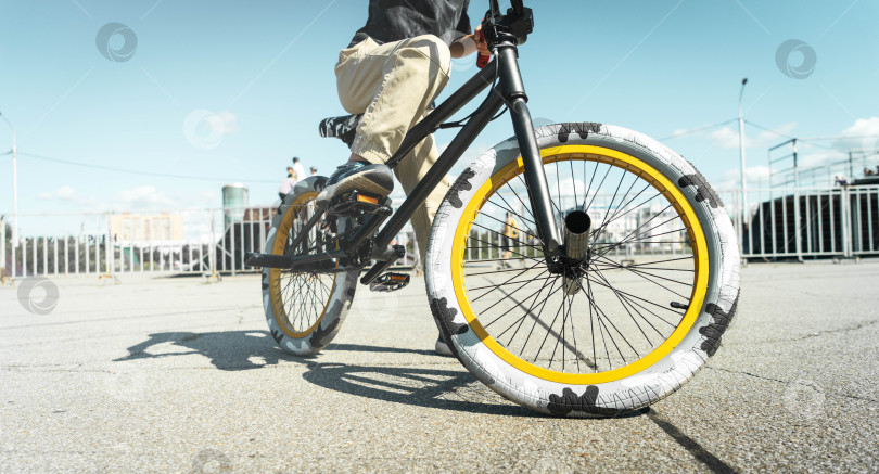 Скачать Мальчик в кепке и футболке катается на велосипеде bmx и учится выполнять трюки возле специальной рампы для трюков. фотосток Ozero