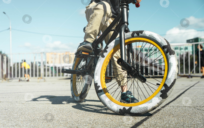 Скачать Мальчик в кепке и футболке катается на велосипеде bmx и учится выполнять трюки возле специальной рампы для трюков. фотосток Ozero