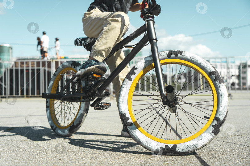 Скачать Мальчик в кепке и футболке катается на велосипеде bmx и учится выполнять трюки возле специальной рампы для трюков. фотосток Ozero