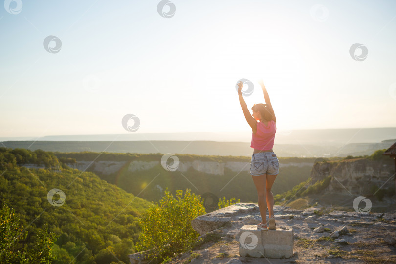 Скачать Туристка с поднятыми руками смотрит на панорамный вид с вершины горы и радуется, наслаждается свободой и приключениями. Треккинг, путешествия, активный экотуризм, здоровый образ жизни, пешие прогулки фотосток Ozero