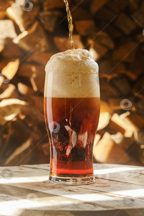 Скачать Бокал янтарного пива на размытом фоне дров. фотосток Ozero